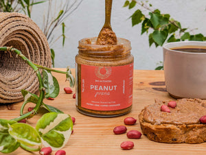 Activated peanut butter with organic peanut butter on a spoon, peanuts, chaga coffee  and a piece of bread on a wooden surface.