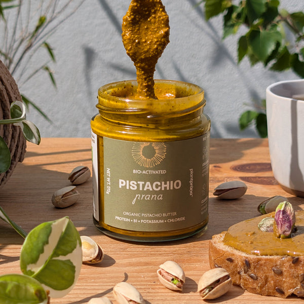 Organic Pistachio Butter with a spoonful, on toast and surrounded by pistachios